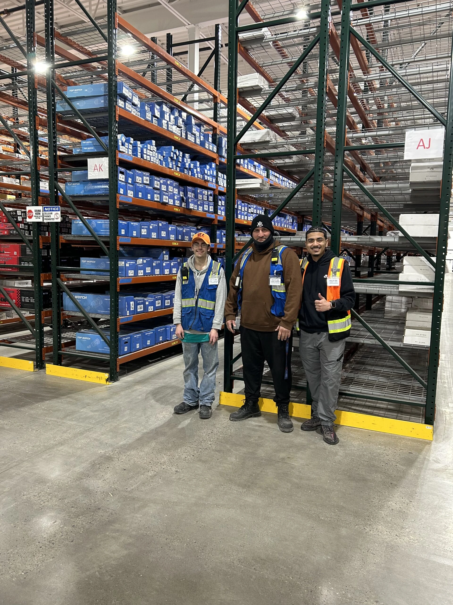 Employees smiling while take a group picture in front of inventory rack.