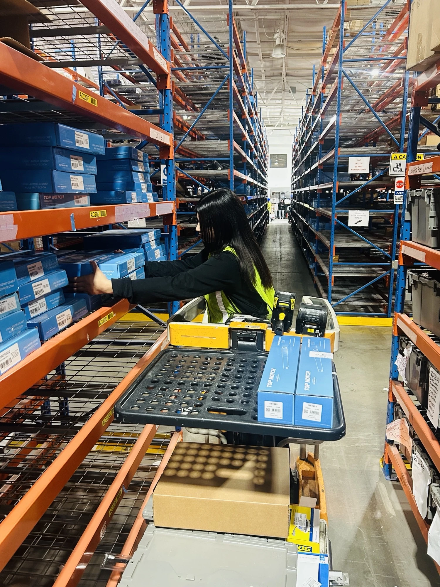 Employee on a lift between racks scanning auto part inventory at the United Auto Supply Distribution Center in Tonawanda.