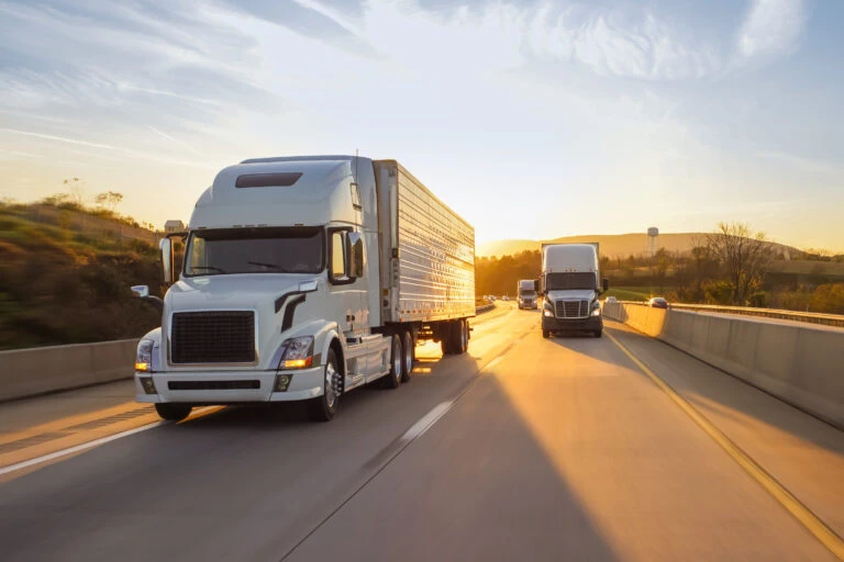 semi trucks on a highway when the sun setting behind them