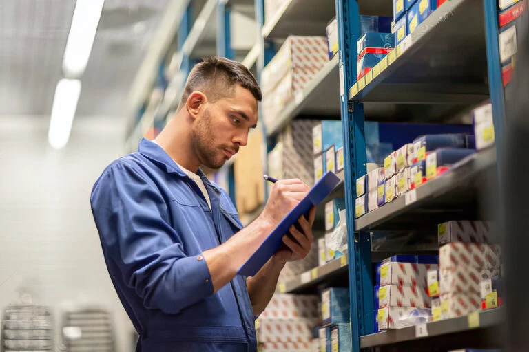 person working in a warehouse counting inventory on a shelf