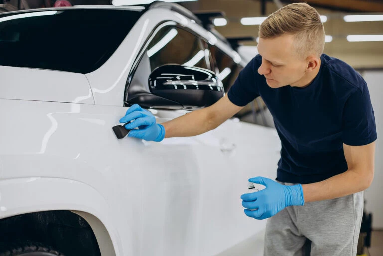 auto mechanic working on detailing the outside of a car door