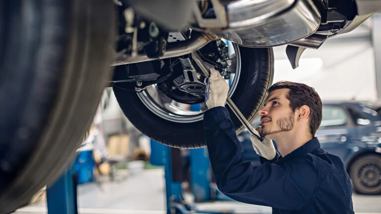 auto mechanic repairing a car from underneath